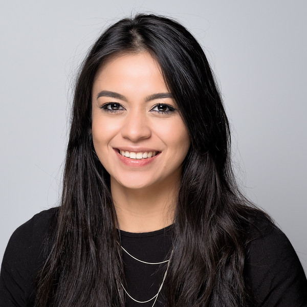 Corporate headshot of a smiling woman with long dark hair in a black top